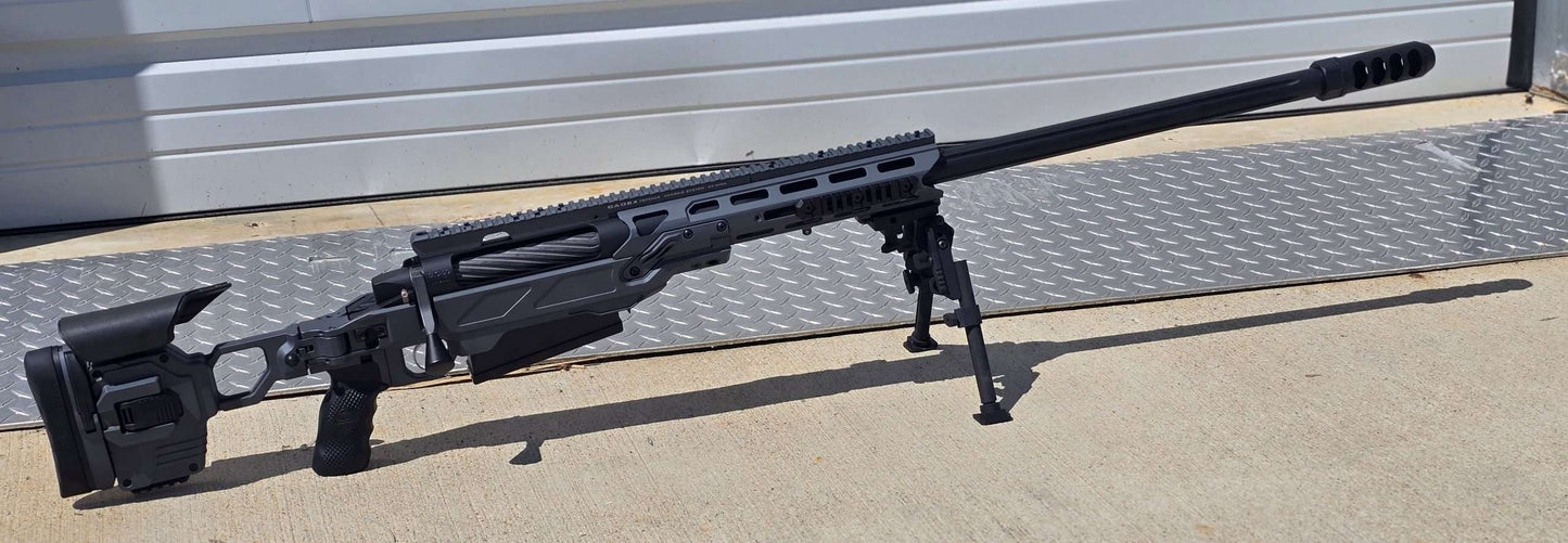 A modern bolt-action sniper rifle with an olive drab chassis, the B&B Firearms MCMILLAN TAC50C features a tactical adjustable stock, a black pistol grip, a twisted fluted barrel, and an expansion muzzle brake. This .50 BMG tactical rifle also includes a bipod for stability and a Picatinny rail for mounting optics.