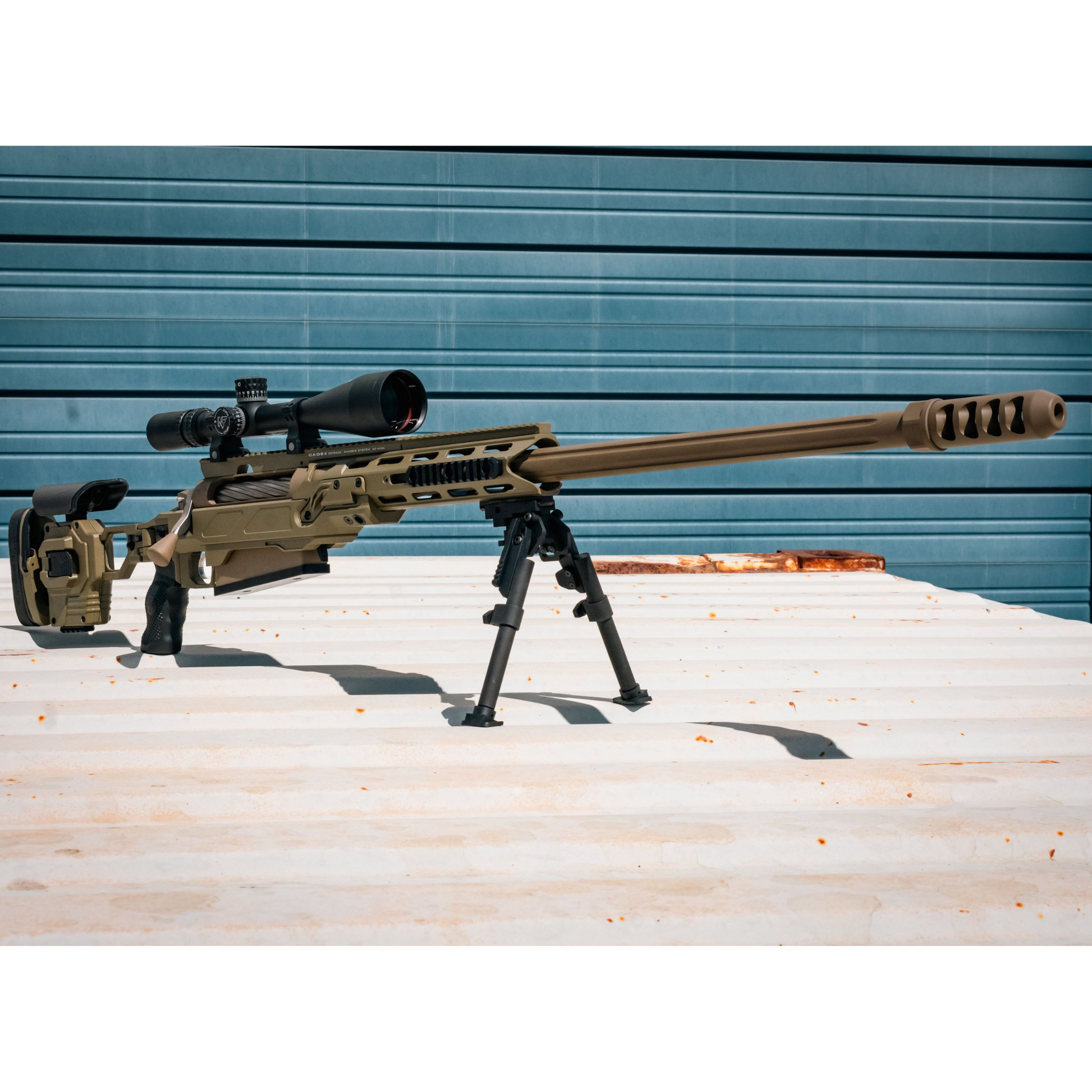 A modern bolt-action sniper rifle with an olive drab chassis, the B&B Firearms MCMILLAN TAC50C features a tactical adjustable stock, a black pistol grip, a twisted fluted barrel, and an expansion muzzle brake. This .50 BMG tactical rifle also includes a bipod for stability and a Picatinny rail for mounting optics.