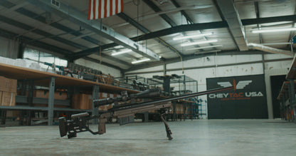 The Cheytac Perses by B&B Firearms is a green and black precision rifle chambered in .338 LM, boasting a long barrel and a large tactical scope mounted on top. Equipped with a bipod, modular stock, ergonomic grip, adjustable cheek rest, and an extended magazine, this firearm is designed for long-range shooting.